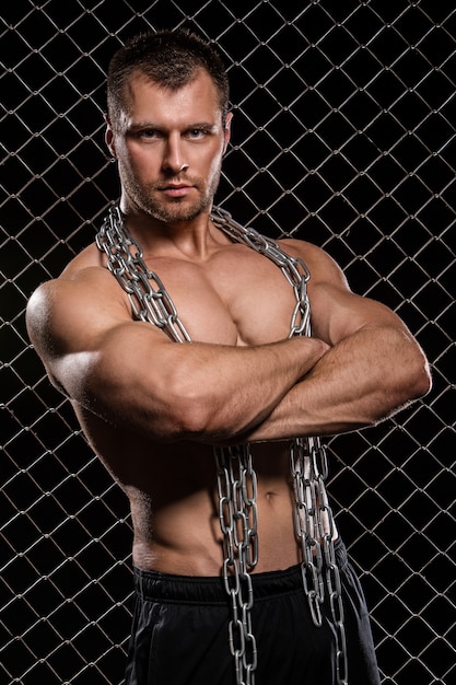 Free photo strong man on fence with chains