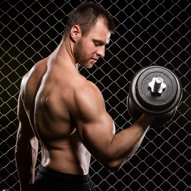 Strong man and his muscles with a dumbbell