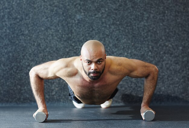 Strong Man Pushing Up on Dumbbells with Effort