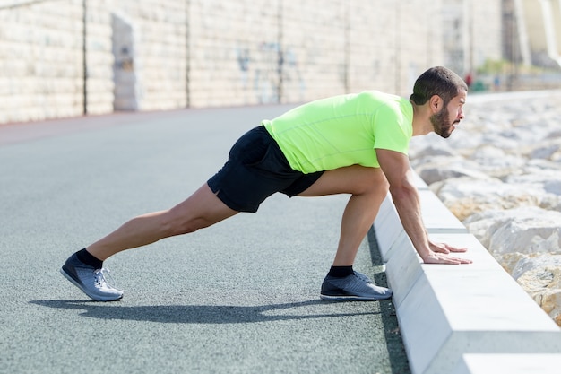 Strong man stretching calf and leaning on curb