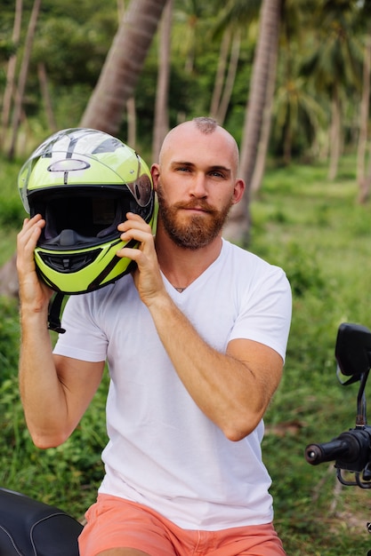 Uomo forte sul campo della giungla tropicale con moto rossa