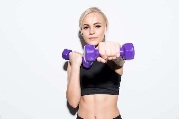 Strong muscular blonde girl kickjob with blue dumbbells on white
