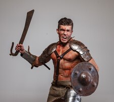 Foto gratuita il forte gladiatore muscoloso attacca tenendo la spada e lo scudo