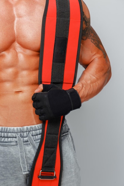 무료 사진 강한 근육질의 남자는 그의 몸을 보여주고 어깨에 파워 벨트를 들고 포즈를 취합니다.