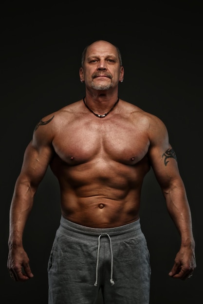 Free photo strong muscular middle age man posing in studio. isolated on grey.