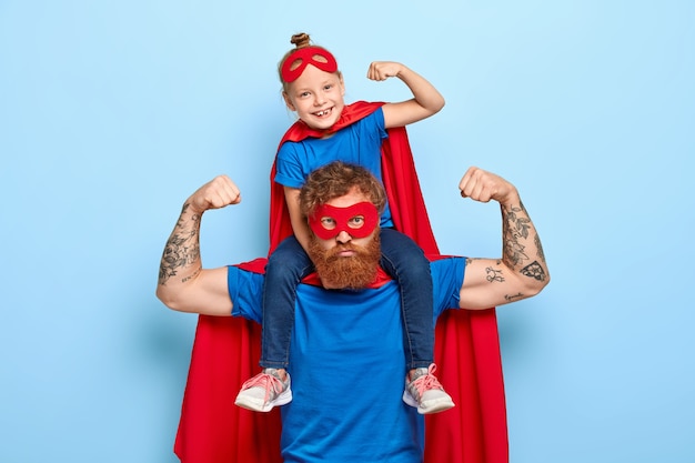 Strong powerful dad and little female child on his shoulders show muscles