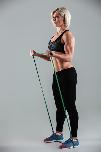 Free photo strong sports woman exercising with resistance band, looking aside