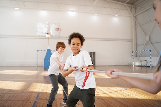 Free photo strong sporty kids pulling rope at gym