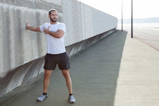 Strong Sporty Man Stretching Arm Outdoors