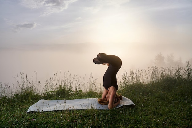 Strong woman practicing headstand pose outdoors