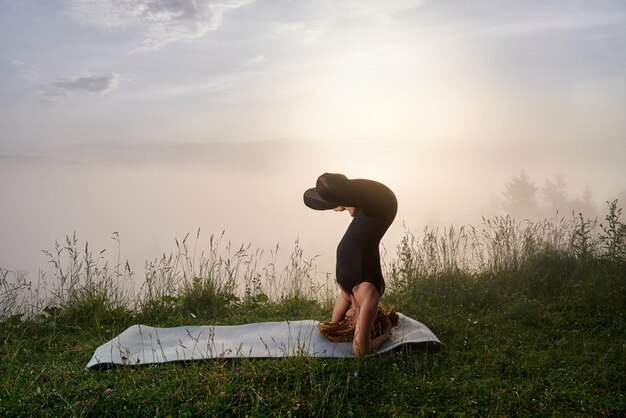 Strong woman practicing headstand pose outdoors