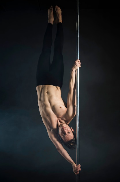 Strong young man performing a pole dance