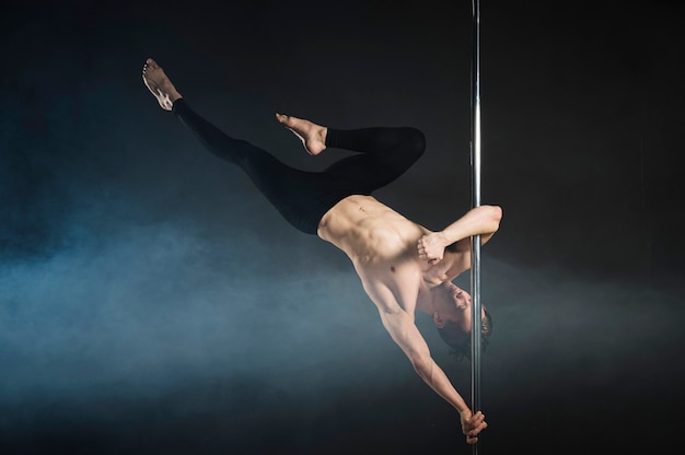 Strong young man performing a pole dance