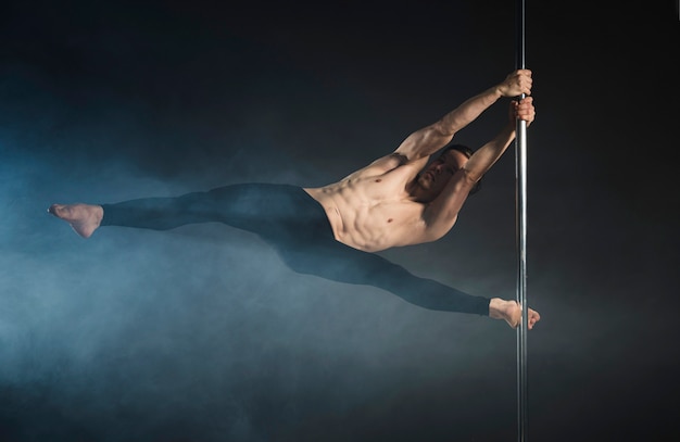 Strong young man performing a pole dance