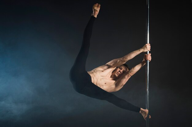 Strong young man performing a pole dance