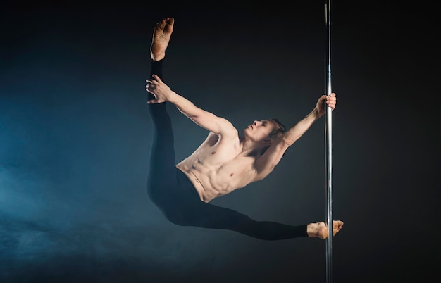 Strong young man performing a pole dance