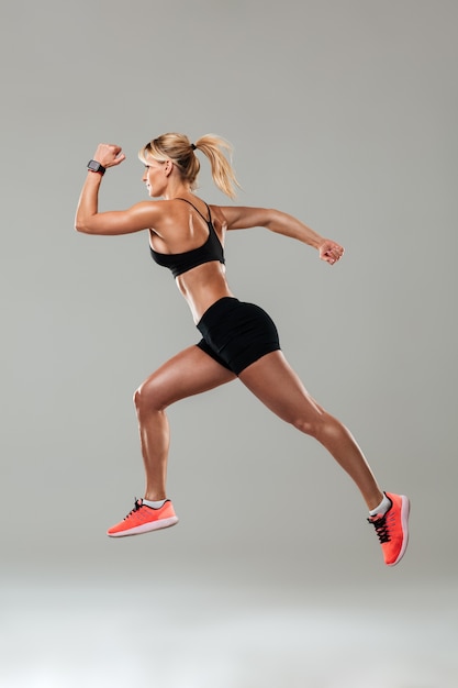 Strong young sports woman running isolated
