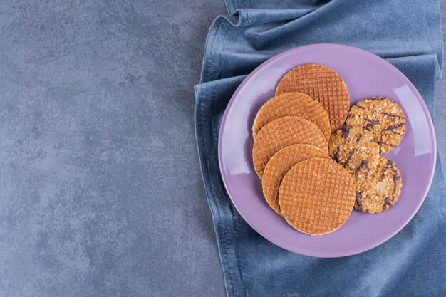 Stroopwafels isolated in a purple plate on stone.