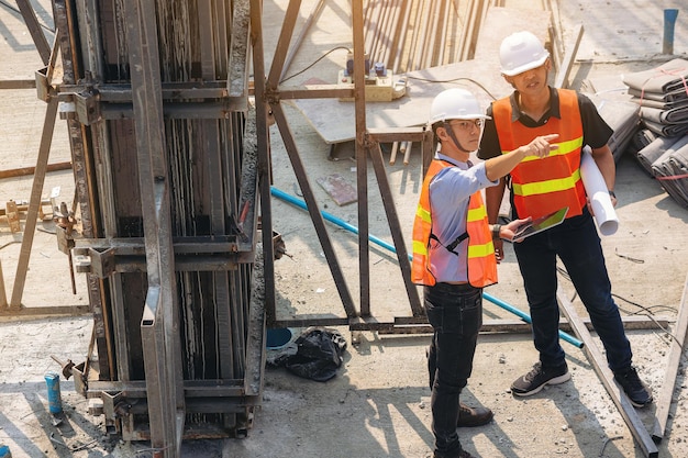 Structural engineer and foreman worker with blueprints discuss plan inspecting for the building