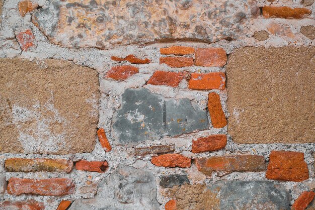 Structure of the wall of an old house made of wild stone and brick an idea for a background or framing space