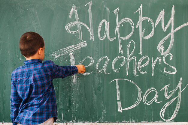 Student boy writing on blackboard congratulation to teacher