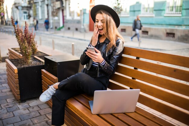 Студент девушка бизнес-леди сидит на деревянной скамейке в городе в парке осенью