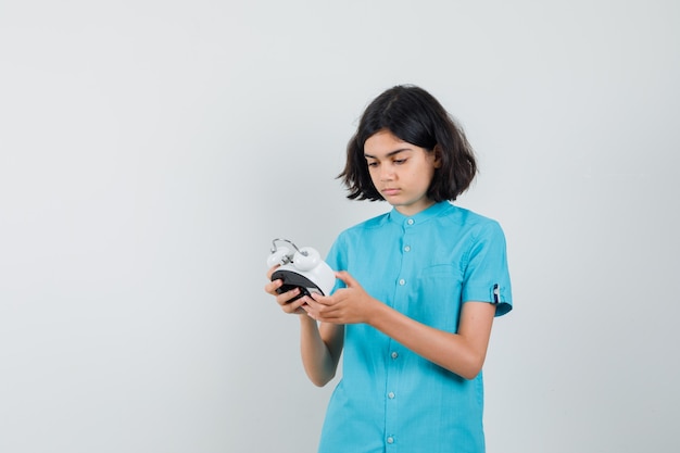 Student girl looking at clock in blue shirt and looking attentive.