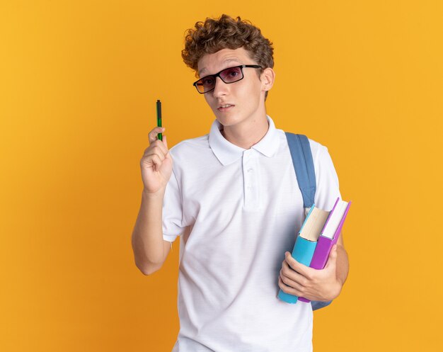 本を保持しているバックパックと眼鏡をかけてカジュアルな服を着た学生の男