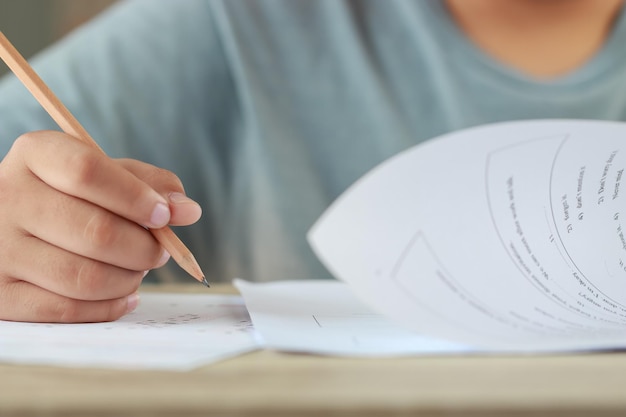 大学での学校の最終試験の解答用紙に選択された選択肢を鉛筆で描くテスト試験を行う学生の手テスト。試験教室での評価のために複数の選択肢を取る