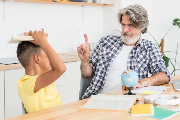 先生の近くの頭の上の本を保持している学生