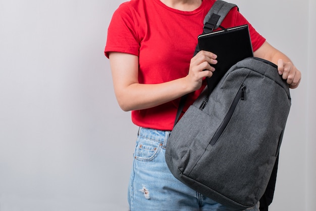 Student holding the grey backpack in the front