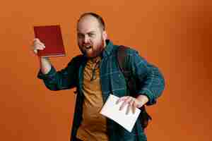 Free photo student man in casual clothes with backpack holding notebooks looking annoyed standing over orange background