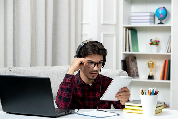 Student online cute guy in checked shirt with glasses studying on computer concentratred