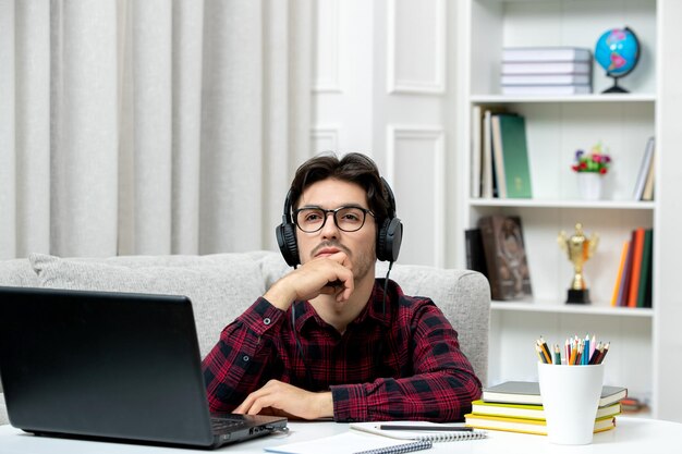 見上げるコンピュータで勉強している眼鏡をかけたチェックシャツの学生オンラインかわいい男