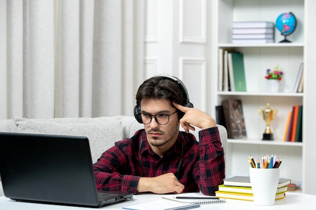 集中してコンピュータ思考を勉強している眼鏡をかけたチェックシャツの学生オンラインかわいい男