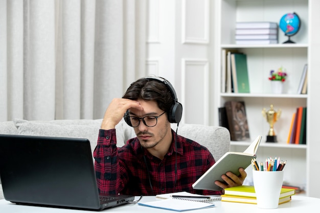 피곤하고 혼란스러운 컴퓨터에서 공부하는 안경을 쓴 체크 셔츠를 입은 온라인 귀여운 남자