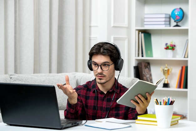 手を振っているコンピューターで勉強している眼鏡とチェックシャツの学生オンラインかわいい男