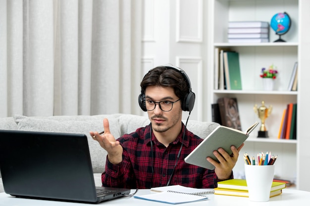 Student online cute guy in checked shirt with glasses studying on computer waving hands