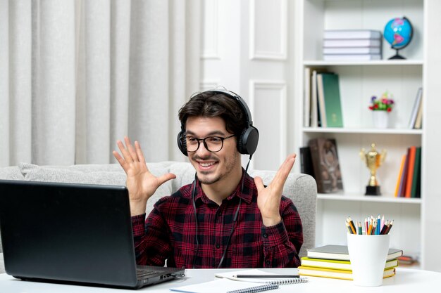 Student online young guy in checked shirt with glasses studying on computer excited for grade