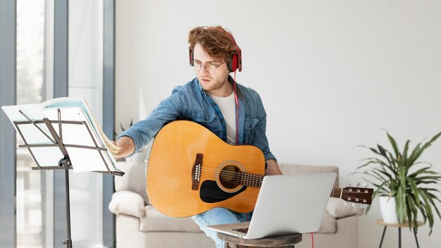 student playing guitar and wearing headphones medium shot