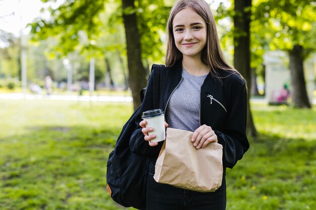 Student posing with coffee and paper bag