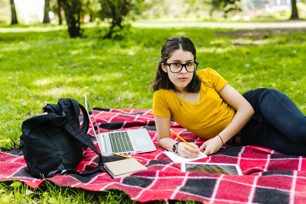 Студент позирует с очками на траве