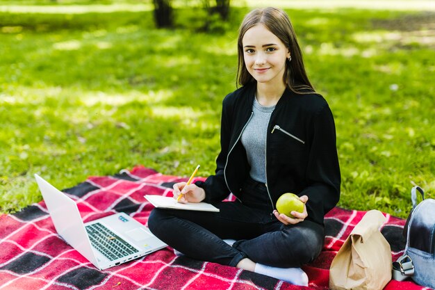 Student posing with notebook and apple