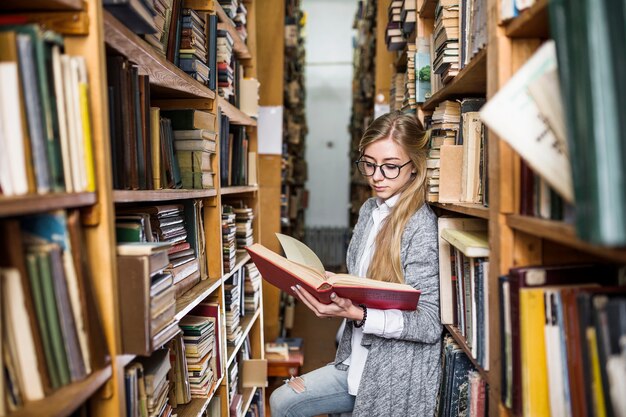 Student reading book between bookcases