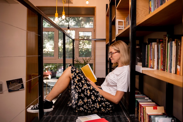 Foto gratuita studente che legge un libro in biblioteca