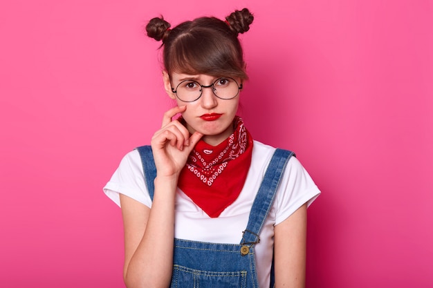 Student standing isolated over pink in studio, touching her face with fingers