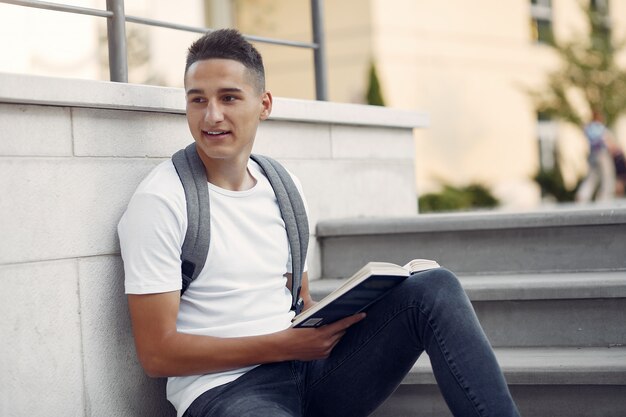 Студент в университетском городке с книгой