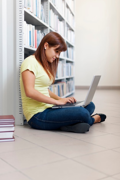 Бесплатное фото Студент, использующий ноутбук в библиотеке