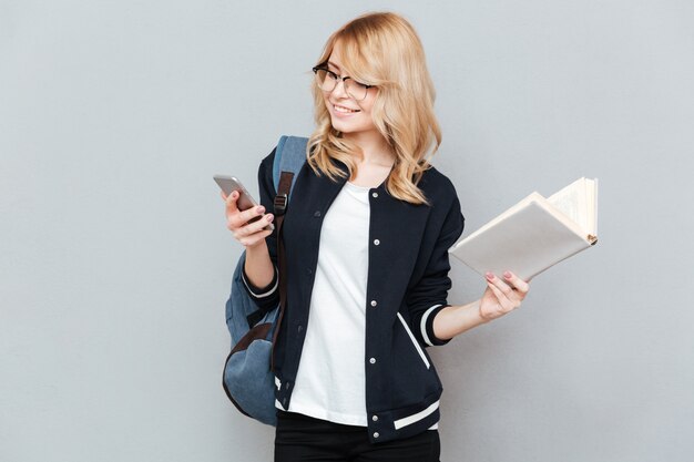 Student using phone and holding book