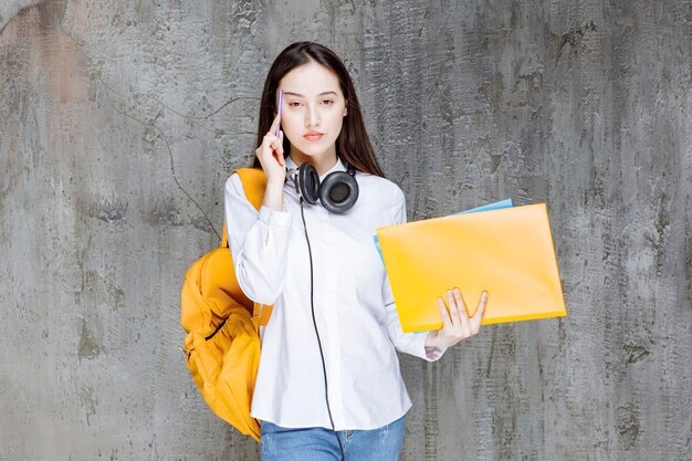 Student with backpack and headphones books in her hand looking. High quality photo